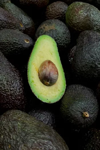 Avocados in a pile with a cut avocado on top