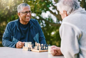 two older men playing chess in a park