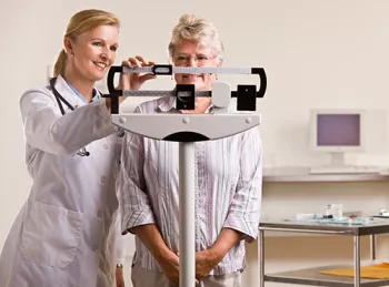 doctor weighing an older woman