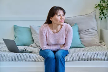 woman sitting on couch holding her stomach