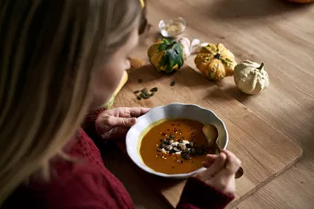 looking over a woman's shoulder who is eating a bowl of lentil soup