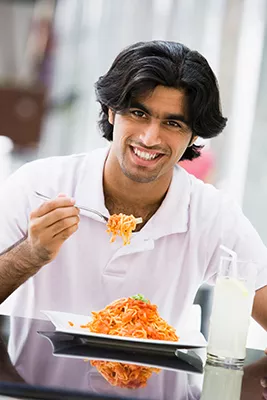Man with larch plate of spaghetti and holding a forkful of spaghetti