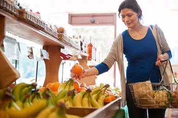 woman pocking up and orange in the supermarket
