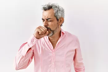 man holding a fist to his mouth while he coughs