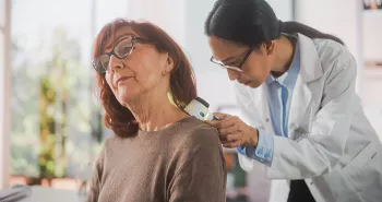 doctor looking at the skin of an older woman's back