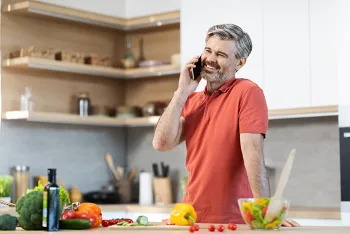 man talking on the phone while standing in the kitchen
