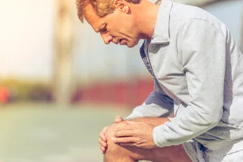 man kneeling and holding knee
