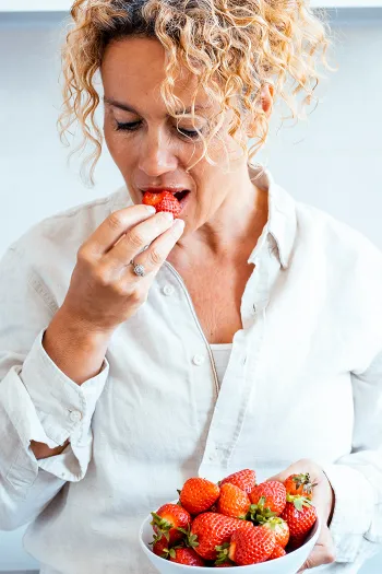 Woman taking a bite of a red berry