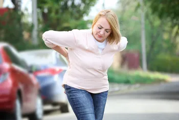 woman leaning over holding her back in pain