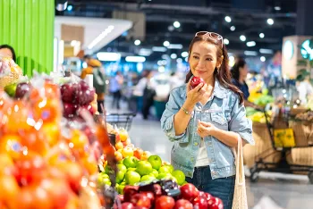 woman at grocery store holding a apple in the produce section