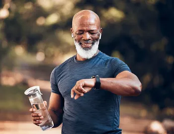 older man walking in park while holding a waterbottle