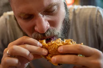 man taking a bite out of a burger