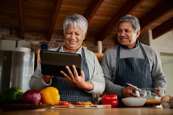 couple looking at an iPad and cooking in the kitchen