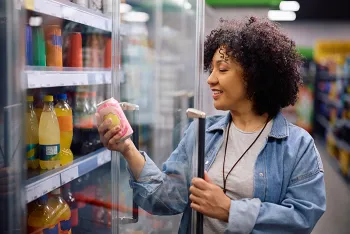 woman looking at soda can in grocery isle