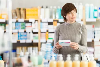 woman holding a box while standing in a drugstore
