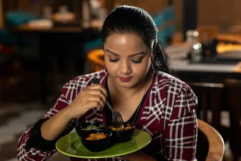 woman eating colorful foods out of 3 small bowls