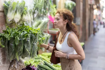 woman picking out a bunch of leafy greens in a grocery store