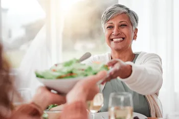 woman passing a bowl of salad at a table