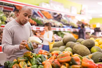 man picking out vegetables at grocery store