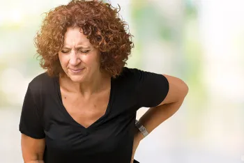 woman holding her back in pain