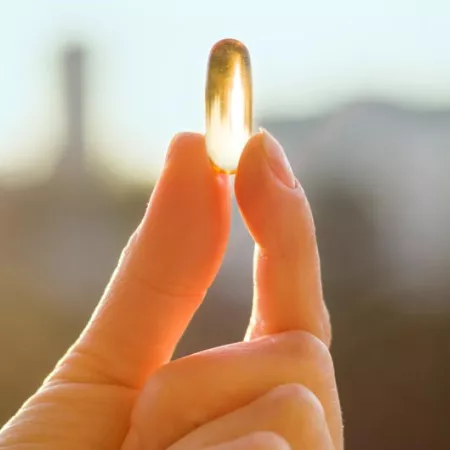a hand holding a vitamin d pill