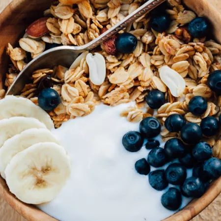 a bowl of oatmeal granola with peanuts blueberry and banana