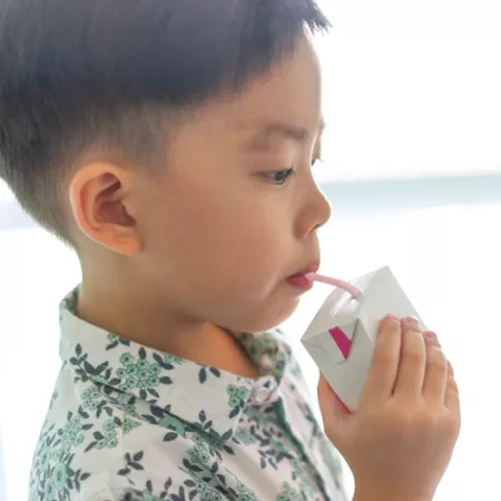young child sipping from a juice box with straw