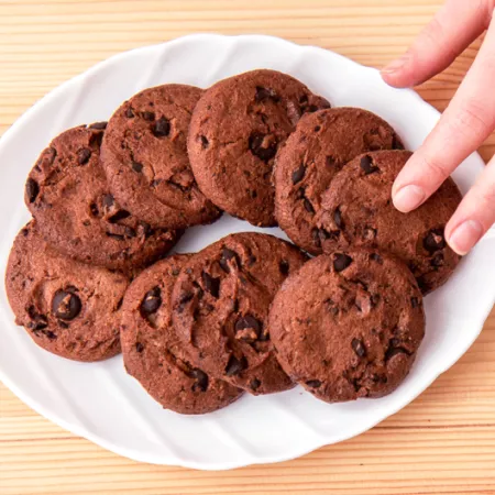 hand reaching over white plate full of chocolate cookies