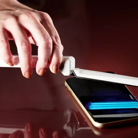 person using UV wand over cell phone