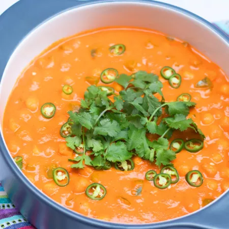 large blue pot of paprika chickpeas with green garnishes
