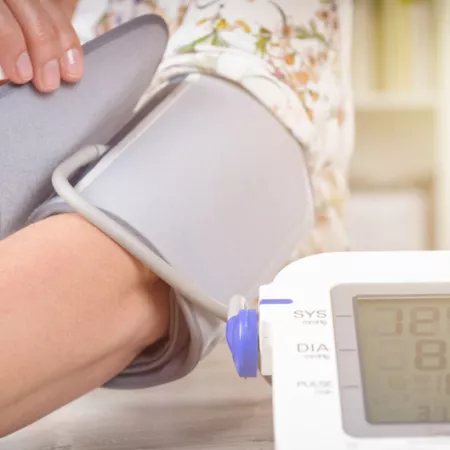 person fastening a blood pressure monitor on their arm
