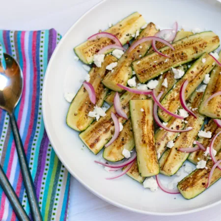 plate filled with greek zucchini slices with a colorful napkin and utensils
