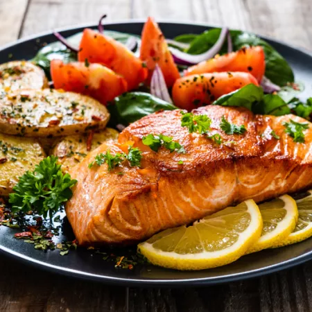 plate with cooked salmon tomatoes and potatoes