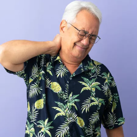 Older man holding the back of his neck and wincing