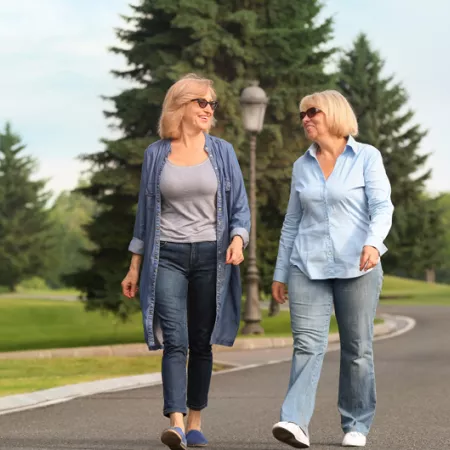 two women walking on a tree lined street