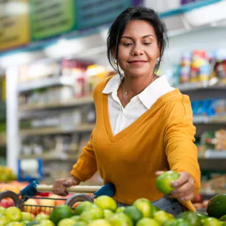 woman picking up a green apple in a grocery store