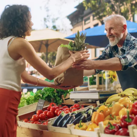 woman buying a pineapple at an outdoor farmers market
