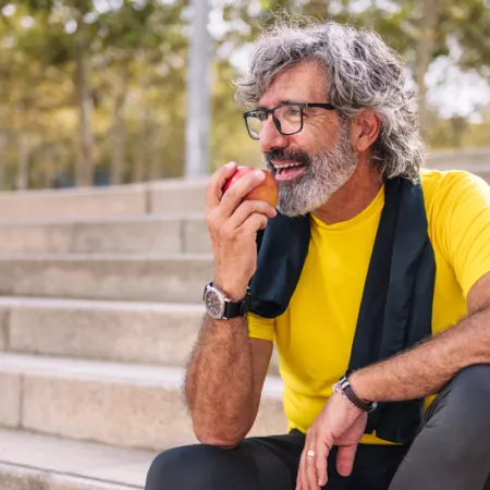 man sitting on steps outside eating an apple