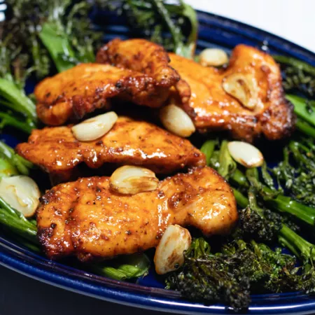 dark blue plate with broccolini and chicken