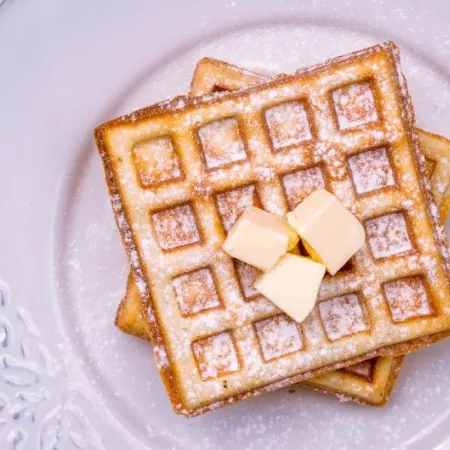 Prepared frozen waffles; flat lay on a white ceramic plate with butter