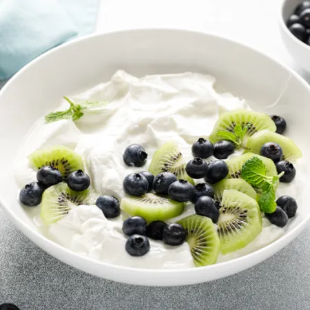 bowl of yogurt with blue berries and kiwis