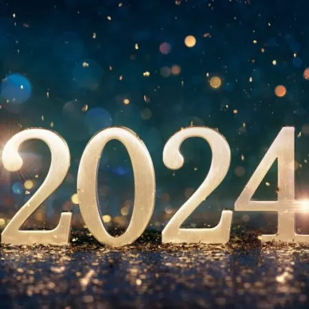 2024 in gold numerals on a reflective surface in front of deep blue bokeh background