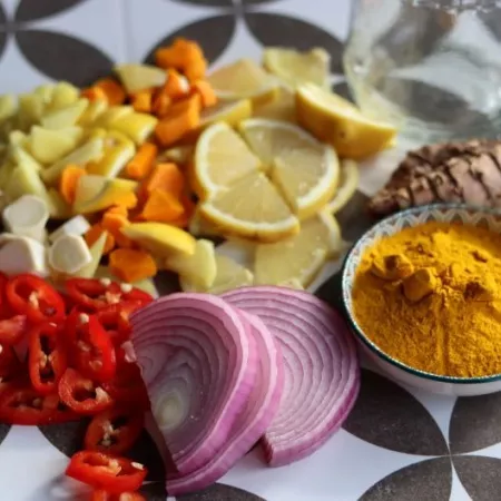 Fire cider chopped ingredients on grey tiled background. Top view photo of turmeric, ginger, pepper, garlic, onion and lemon.