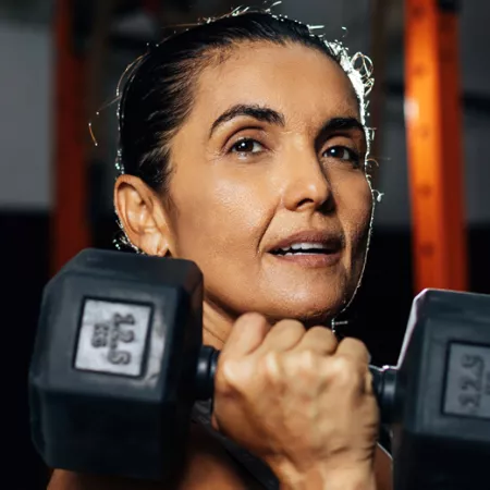 woman holding a dumbbell under her chin 