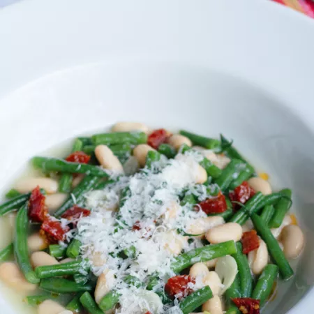 white bowl filled with beans and greens
