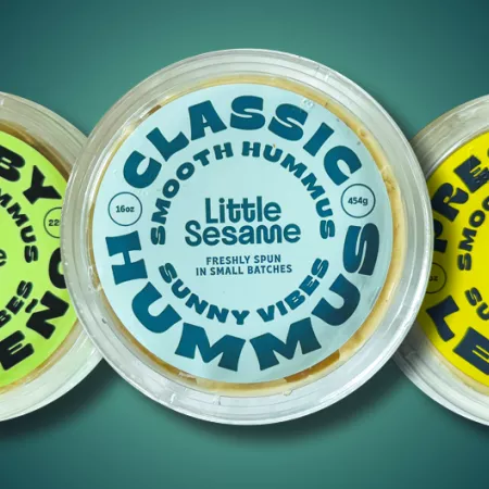 3 tubs of different flavors of Little Sesame hummus with original flavor in the middle.