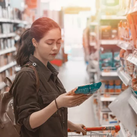 a woman reading a food package label in a grocery store