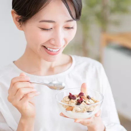 woman eating a small yogurt parfait out of a clear bowl