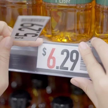 Closeup of grocery store worker increasing prices on cooking oil from $5.29 to $6.29. Rising food costs concept. 