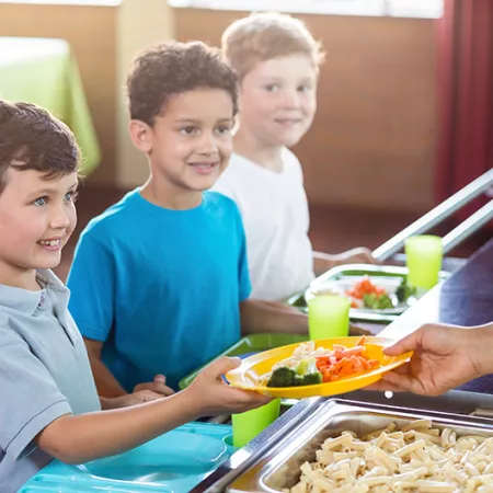 Woman serving food to schoolchildren